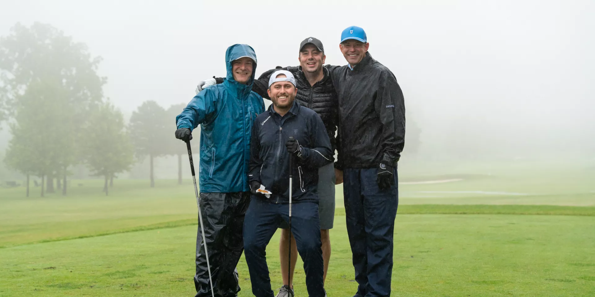 Golf Classic 2023 Golfers posing in the rain at the Golf Classic 2023