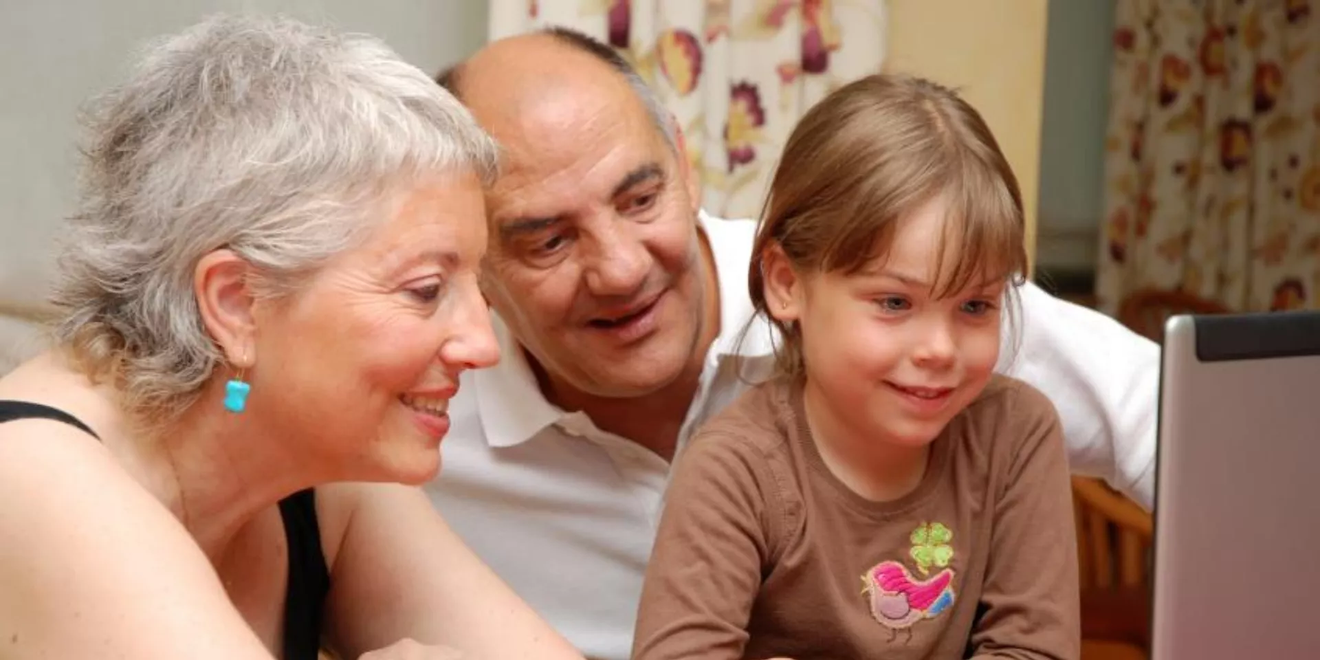 Senior couple looks at computer screen with female child