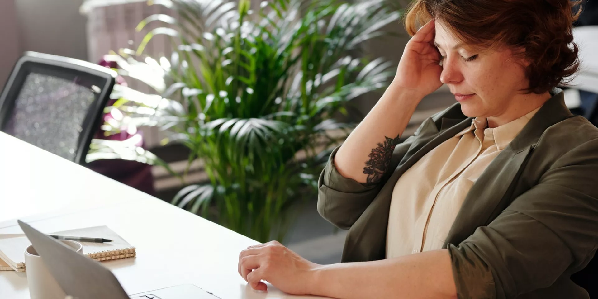 Woman at work desk holding her head
