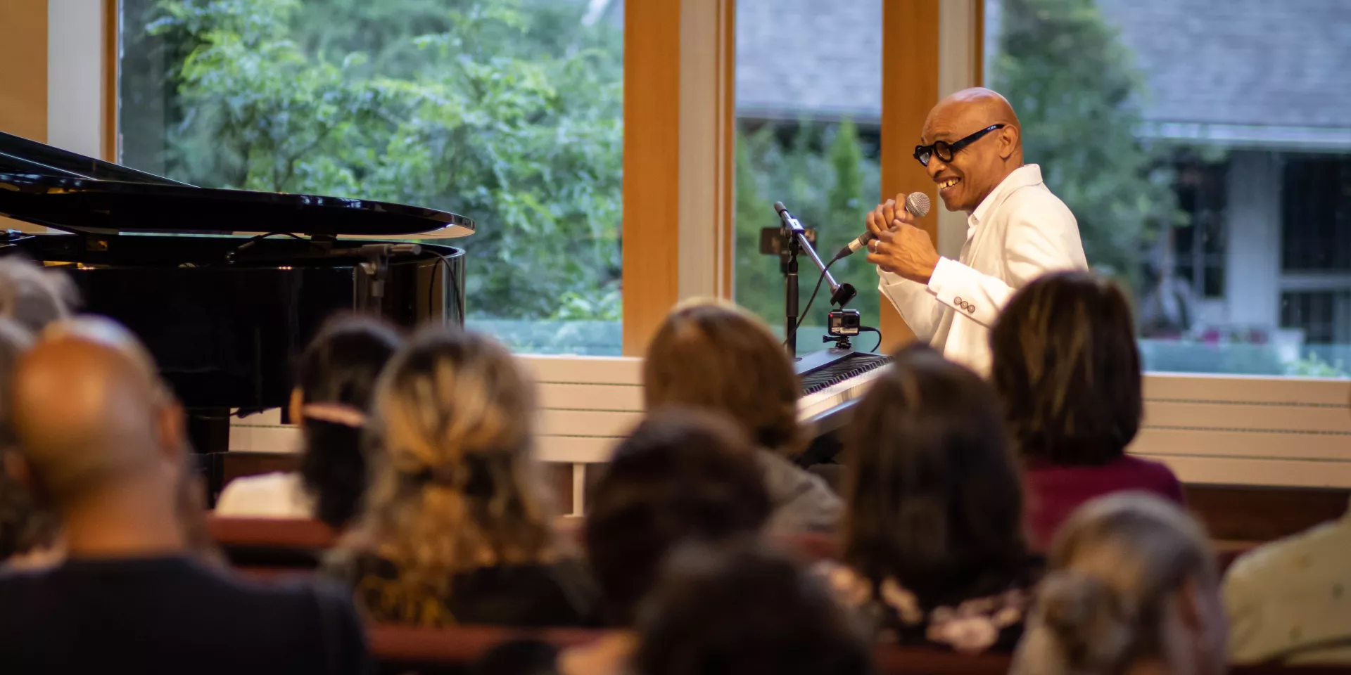Eddie Bullen sitting at his piano speaking to a crowd