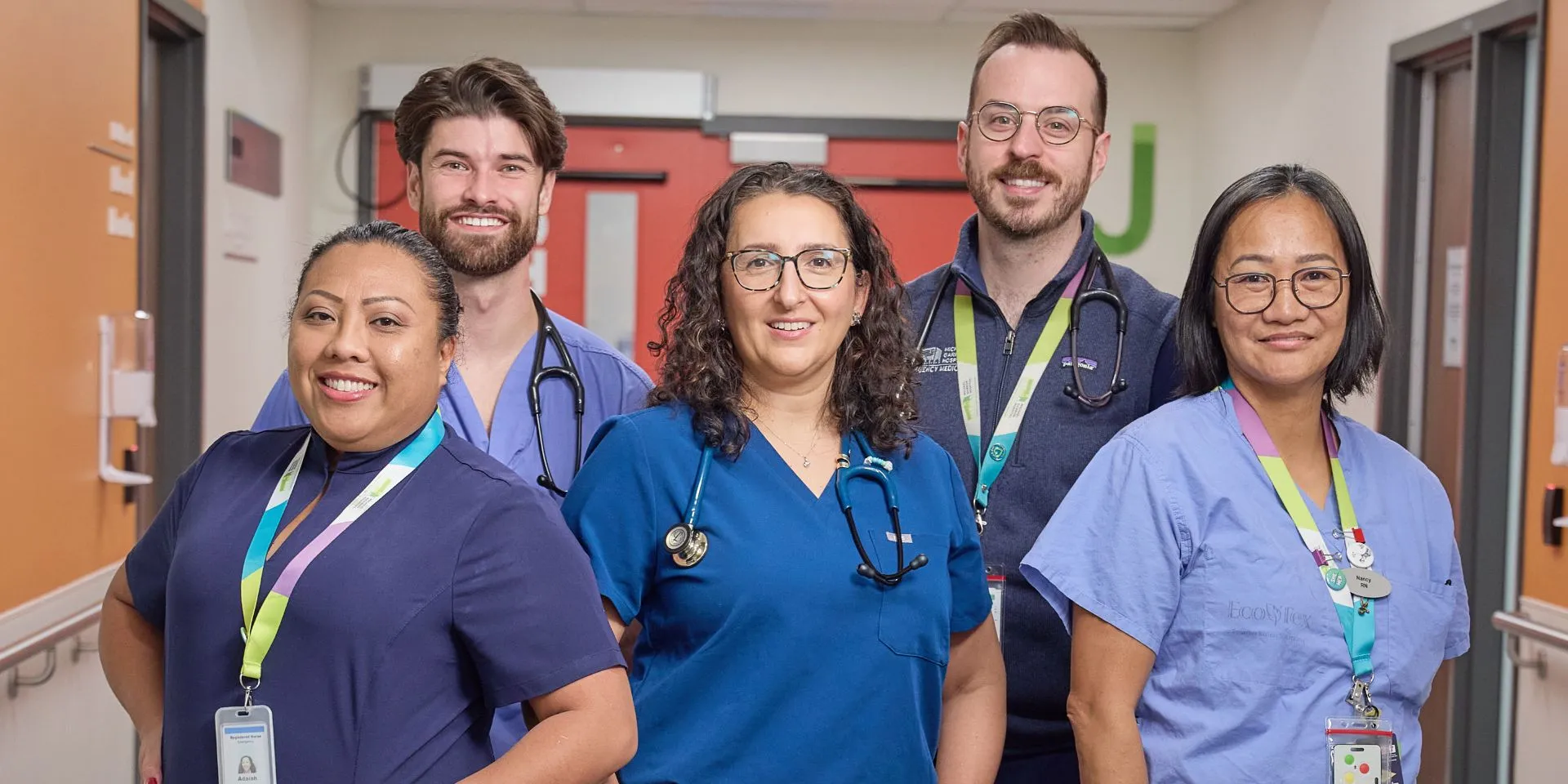 A group of five Michael Garron Hospital Emergency Department employees. Standing and smiling in scrubs