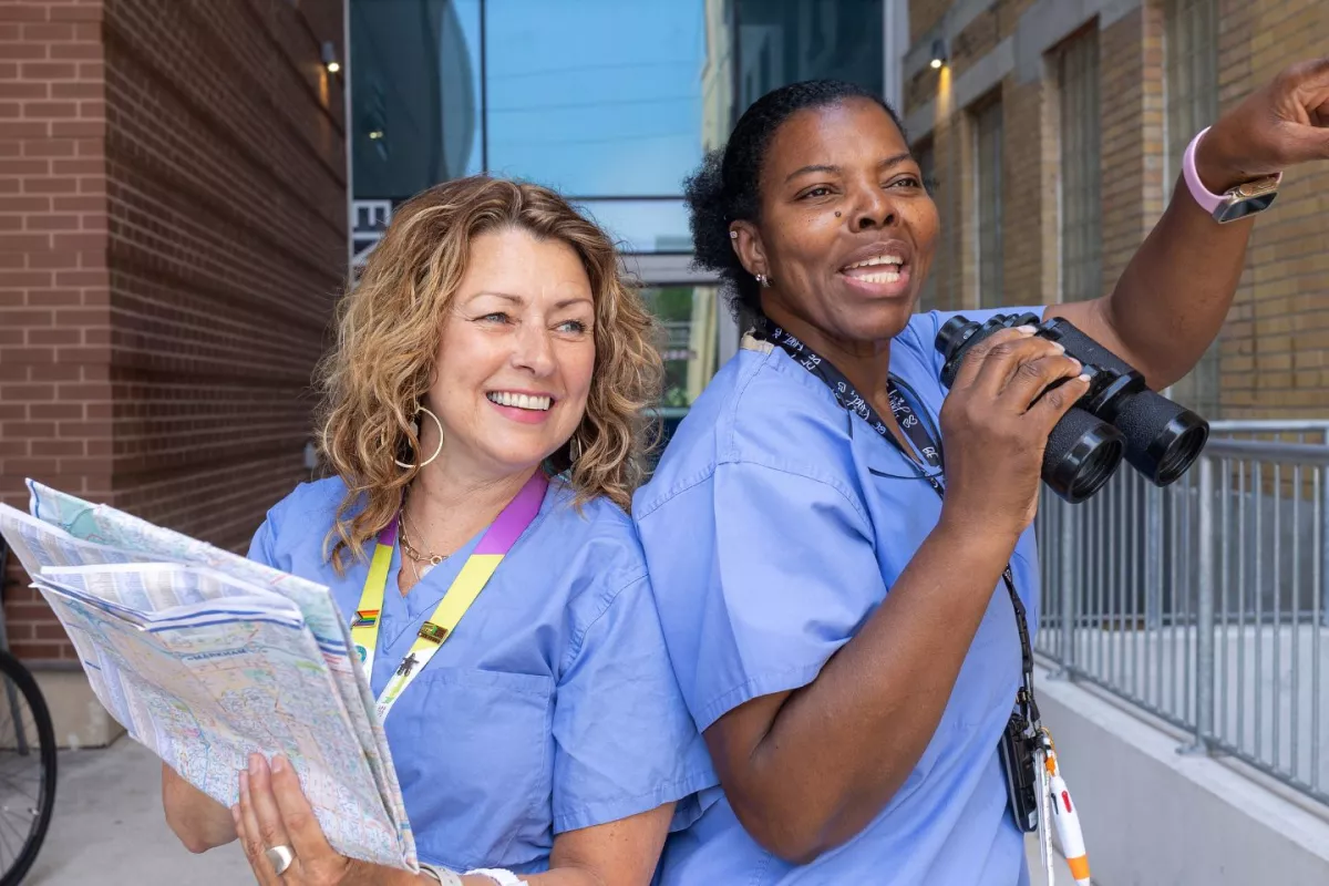 Two nurses back to back, holding a map