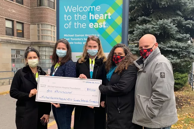 five people standing in front of the hospital holding a giant cheque 