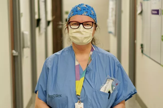 healthcare worker wearing mask standing in hospital corridor