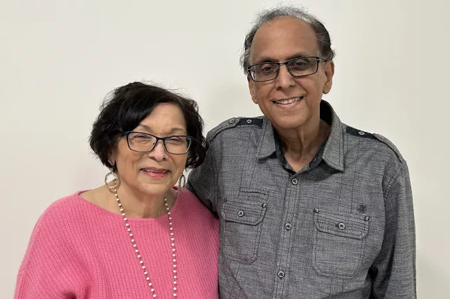 An older couple posed with his arm wrapped around her