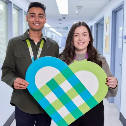 Three staff members holding the heart logo